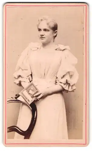 Fotografie unbekannter Fotograf und Ort, Junges Mädel im hellen Rüschenkleid mit Buch in der Hand