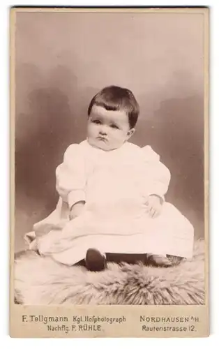 Fotografie F. Tellgmann, Nordhausen a. H., Rautenstrasse 12, Süsses Kleinkind im weissen Kleid sitzt auf Fell