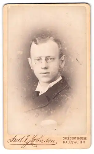 Fotografie Fred E. Johnson, Halesworth, Junger Mann mit Zwicker, gewichstem Seitenscheitel und Korteletten