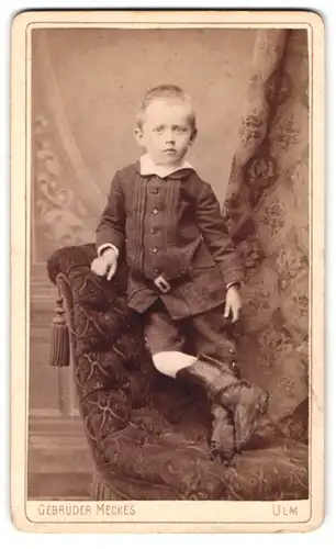 Fotografie Gebrüder Meckes, Ulm, Portrait eines Jungen auf Recamiere stehend