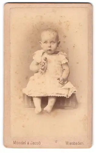 Fotografie Mondel & Jacob, Wiesbaden, Portrait eines Kleinkindes im Kleid mit Spielzeugpuppe