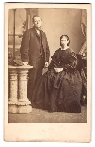 Fotografie J. Navey, Leeds, englsiches Paar im schwarzen Kleid mit Brosche und im Anzug mit Fliege