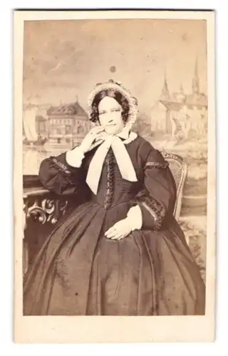 Fotografie L. Hohbach, Constanz, Portrait junge Dame im schwarzen Kleid mit Haueb vor einer Studiokulisse
