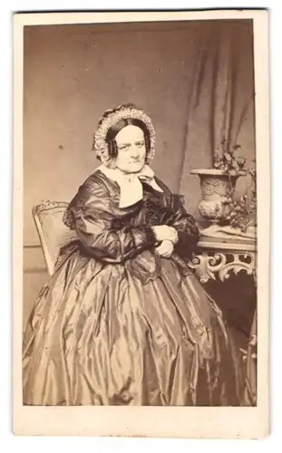 Fotografie L. Hohbach, Constanz, ältere Dame im seidenen Kleid mit Haube sitzt im Atelier
