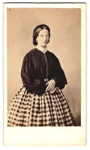 Fotografie F. Halm, Constanz, junge Frau im karierten Rock mit dunkler Bluse und Haarband
