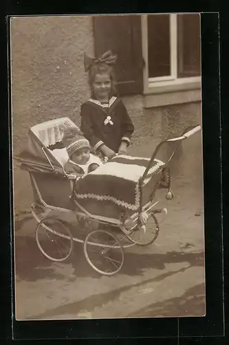 Foto-AK Kleines Mädel stolz neben ihrem kleinen Geschwisterchen im Kinderwagen posierend