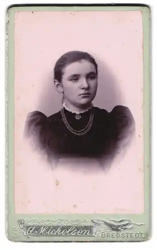 Fotografie A. Michelsen, Bredstedt, Heranwachsendes Mädchen mit Perlenhalskette im schwarz-weissen Rüschenkleid