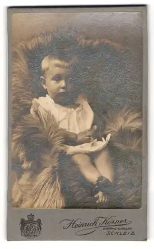 Fotografie Heinrich Körner, Schleiz, Kleinkind im Kleid auf Felldecke