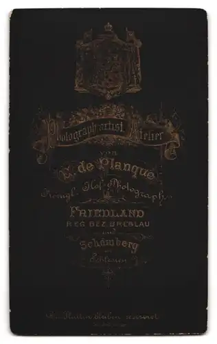 Fotografie E. de.Planque, Friedland, junger Beamter in Dienstuniform steht rauchend im Atelier