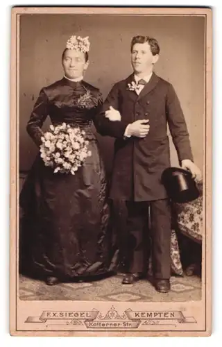 Fotografie F. X. Siegel, Kempten, Brautpaar im schwarzen seidenen Hochzeitskleid und im Anzug mit Zylinder