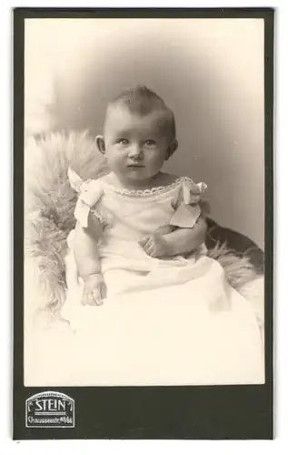 Fotografie Stein, Berlin, Chausseestrasse 65 /66, süsses kleines Mädchen sitzt im weissem kleid auf einem Fell