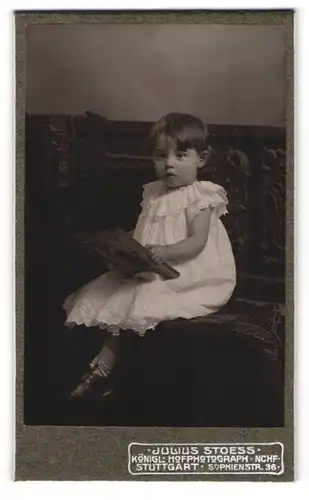 Fotografie Julius Stoess, Stuttgart, Sophienstrasse 36, kleines süsses Mädchen sitzend im weissem Kleid und mit Buch