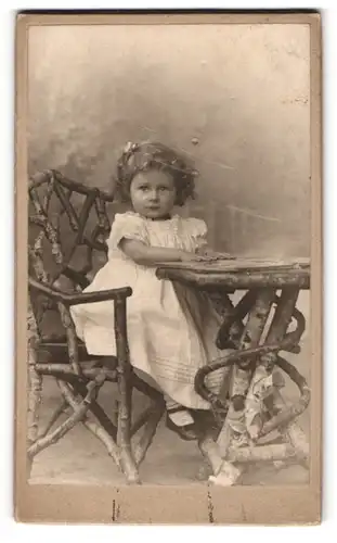 Fotografie Ph. Uhl, Giessen, Frankfurterstr. 5, Portrait süsses Mädchen mit Haarschleife sitzt an einem Tisch