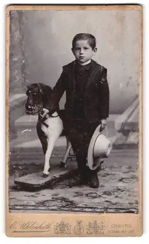 Fotografie E. Uhlenhuth, Coburg, junger Knabe im Anzug mit Sommerhut und Spielzeug Pferd im Atelier