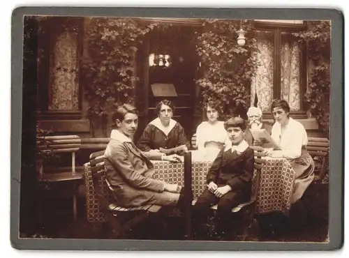 Fotografie unbekannter Fotograf und Ort, Grosseltner und Enkelkinder im heimischen Garten am Tisch sitzend
