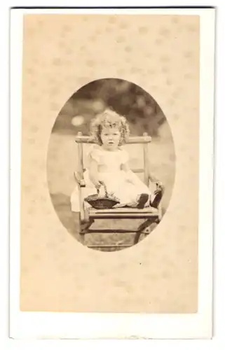 Fotografie F. Waren, Newquay, Goldiges Kleinkind mit krausen Löckchen und Korbgeflecht