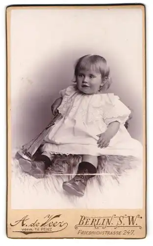 Fotografie A. de Veer, Berlin, Friedrichstrasse 247, Kleines Mädchen im Kleid auf Felldecke