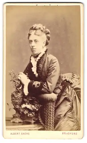 Fotografie Albert Sachs, Bradfort, Junge Dame im Tournürenkleid an Stuhl anlehnend