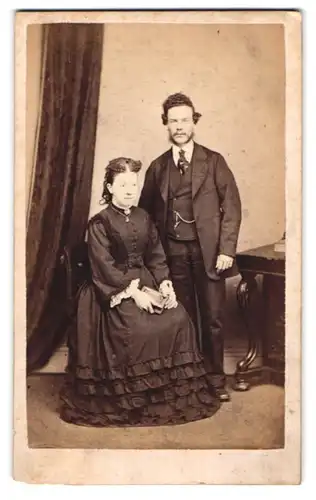 Fotografie Rhodgson, Accrington, Abbey Street, Paar im Tournürenkleid und Anzug im Portrait