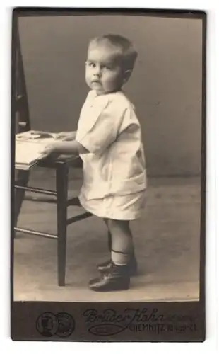 Fotografie Brüder Hahn, Chemnitz, Köngistrasse 21, Kleines Kind in weisser Keidung mit einem Bilderbuch