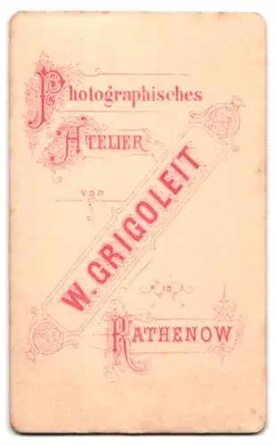 Fotografie W. Grigoleit, Rathenow, Portrait elegant gekleidete Dame steht an einem Tisch