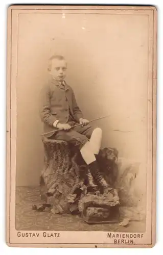 Fotografie Gustav Glatz, Berlin-Mariendorf, Junge im Kindesalter sitzt mit Stock in den Händen neben einem Hund