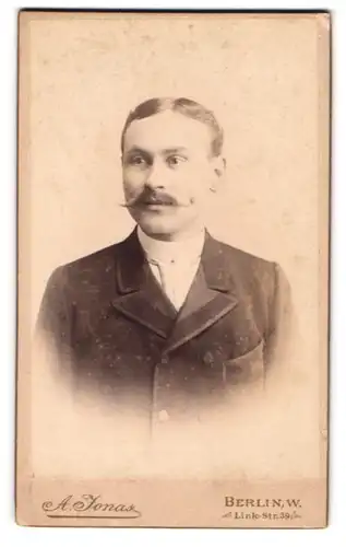 Fotografie A. Jonas, Berlin, Link-Str. 39, Mann mit Schnurrbart und Mittelscheitel in einem Mantel