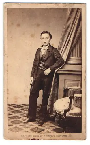 Fotografie J. Gaukler, Stuttgart, Calwerstr. 58, Kleiner Junge schwarz gekleidet mit Fliege, angelehnt an einer Säule
