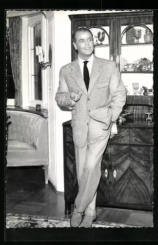 AK Schauspieler O. W. Fischer steht rauchend vor einer Komode