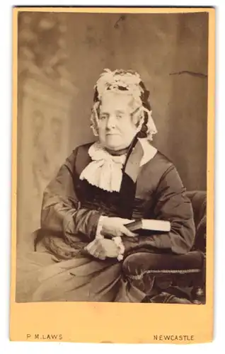 Fotografie P.M Laws, New Castle, Blackett Street 38, Ältere Frau mit Kopfbedeckung mit einem Buch in der Hand