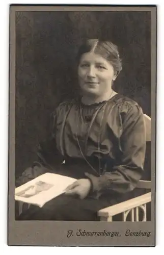 Fotografie J. Schnurrenberger, Lenzburg, Frau mit einem sympathischen Lächeln und einem Bild in der Hand