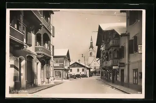 AK Igls, Strassenpartie mit Geschäften und Kirche im Winter