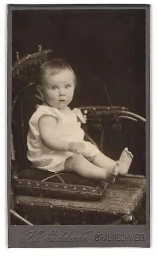Fotografie H. Lüddecke, Braunschweig, Kleines Baby in weisser Kleidung auf einem Stuhl