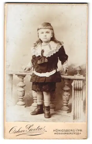 Fotografie Oskar Goetze, Königsberg i. Pr., Weissgerberstr. 22, Kleines Mädchen mit Gürtel an einem Geländer