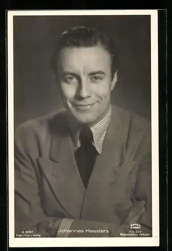 AK Schauspieler Johannes Heesters mit einem sympathischen Lächeln und verschränkten Armen