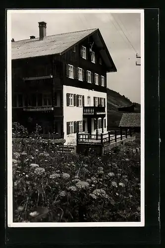 AK Mittelberg, Altes Gebäude mit Blumenwiese