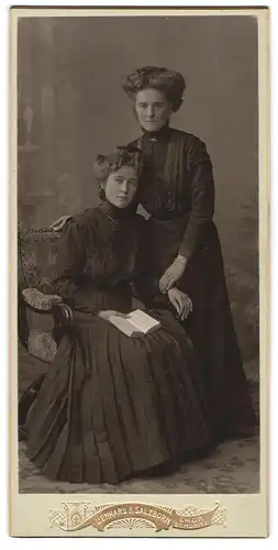 Fotografie Lienhard & Salzborn, Chur, Zwei junge Damen in Kleidern mit Buch