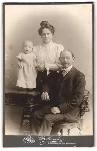 Fotografie C. Münch, Strassburg i. Els., Mutter und Vater mit ihrer Tochter Hedwig auf dem Tisch im Atelier