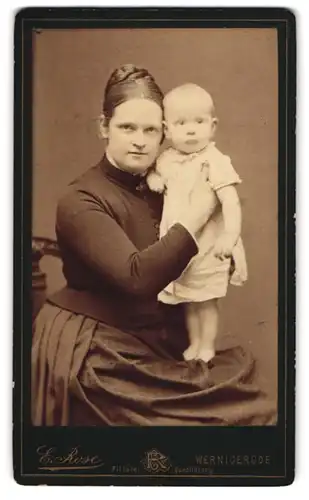 Fotografie Portrait E. Rose, Wernigerode, Mutter im schwarzen Kleid zeigt ihr Kind in die Kamera, Mutterglück