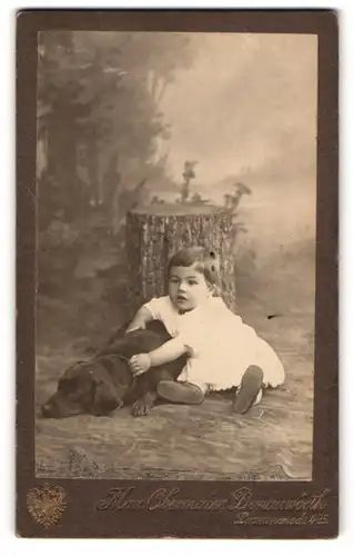 Fotografie Max Obermaier, Donauwörth, Kleinkind im weissen Leibchen streichelt ihren schwarzen liegenden Hund, 1913