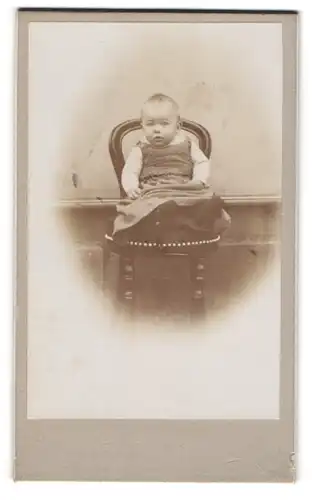 Fotografie unbekannter Fotograf und Ort, Kleines Baby im Kleid auf einem Stuhl