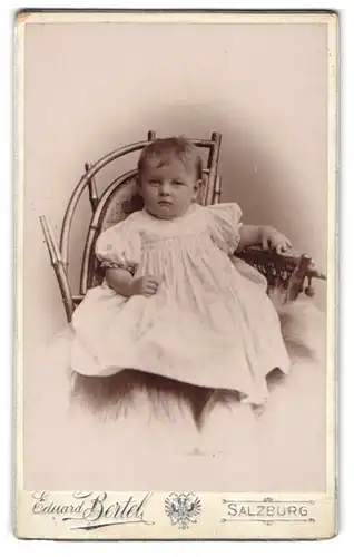 Fotografie Eduard Bertel, Salzburg, Niedliches Baby im weissen Kleid auf einem Stuhl
