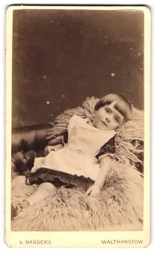 Fotografie V. Manders, Walthamstow, Kleinkind im Kleid auf Schafspelz