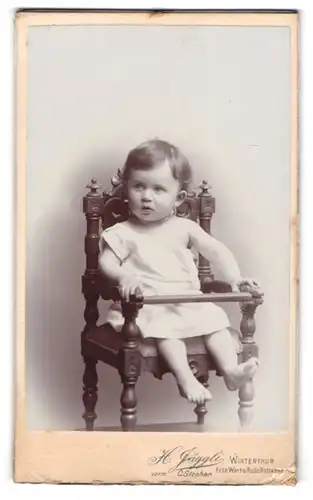 Fotografie H. Jäggli, Winterthur, Ecke Wart u. Rudolfsstrasse, Kleines Baby auf einem Holzstuhl