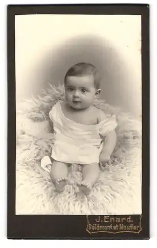 Fotografie J. Enard, Delemont, Avenue de la gare, Kleines Baby auf einem Schaffell
