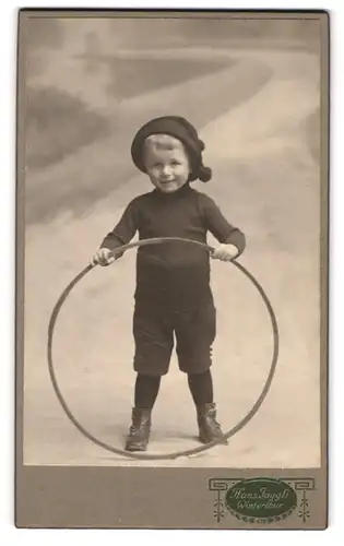 Fotografie Hans Jäggli, Winterthur, Kleiner Knabe mit Mütze und Reifen in den Hand