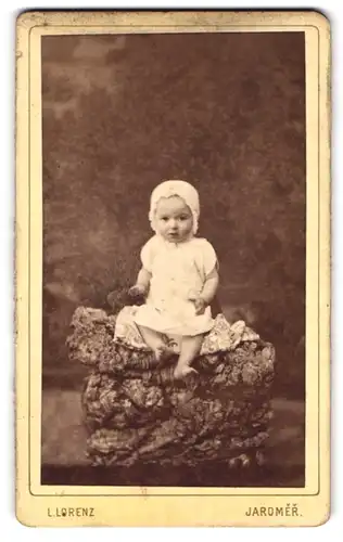 Fotografie L. Lorenz, Jaromer, Prager Vorstadt 102, Portrait niedliches Baby in Mütze und Kleidchen