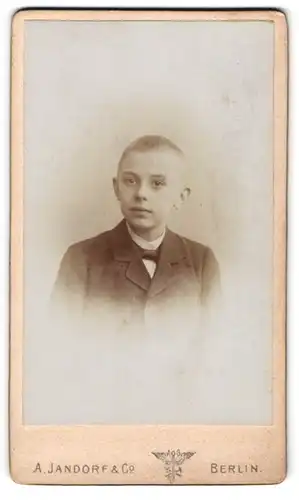 Fotografie A. Jandorf & Co., Berlin, Spittelmarkt 16 /17, Portrait frecher blonder Bube mit Fliege im Jackett