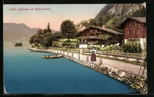 AK Iseltwald am Brienzersee, Dame im Trachtenkleid am Uferweg, traditionelle Häuser dahinter