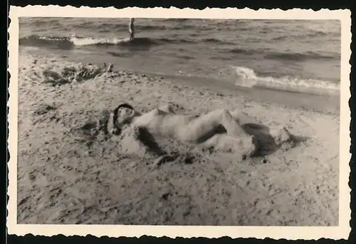 Fotografie Sand-Skulptur, Statue aus Sand am Strand liegend